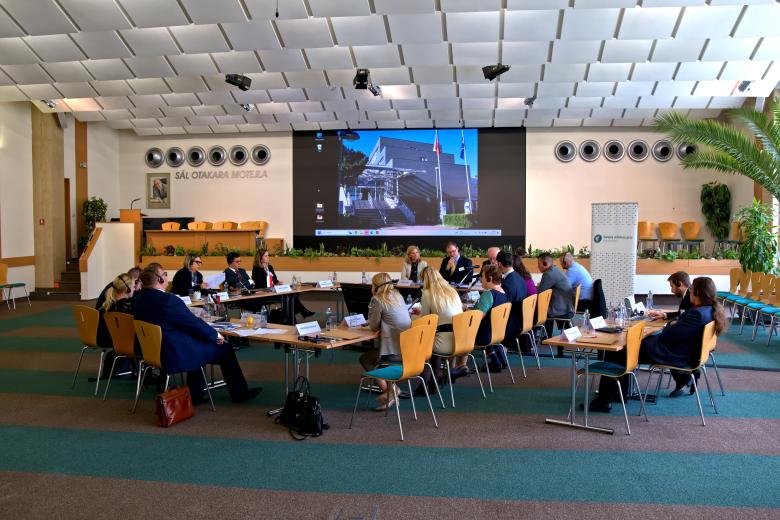 Duży stół ustawiony w kwadrat z ludźmi siedzącymi wokół na sali konferencyjnej