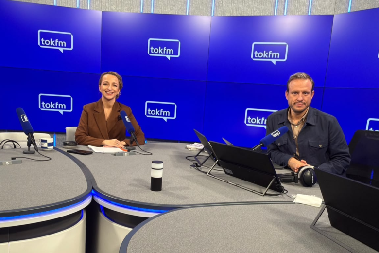Kobieta i mężczyzna siedzą w studiu radiowym i uśmiechają się do zdjęcia