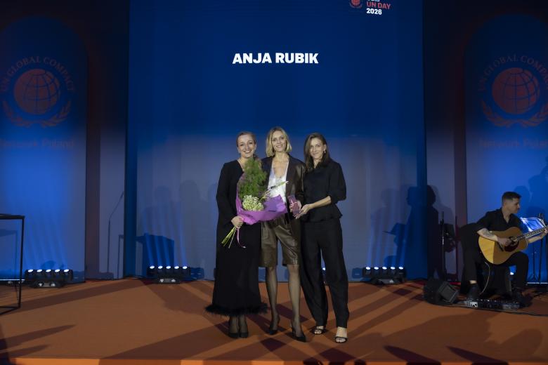 Trzy osoby pozują do wspólnego zdjęcia na scenie, za nimi wyświetlony napis "Anja Rubik"