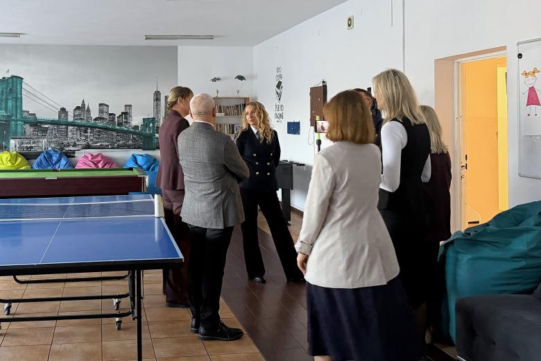 Kilka osób rozmawia w pomieszczeniu ze sprzętem sportowym i rekreacyjnym