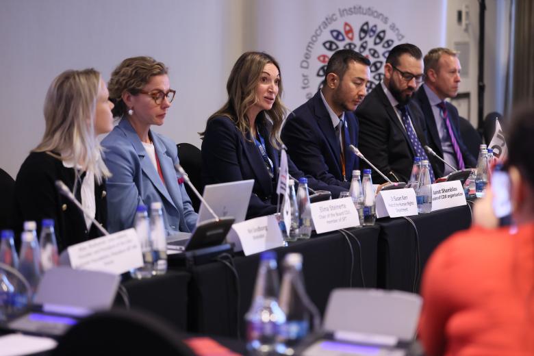 kilka osób siedzi za długim stołem w sali konferencyjnej