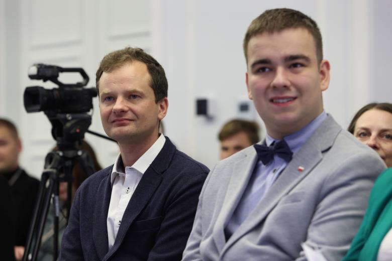 Zbliżenie na osobę siedzącą pośród publiczności na sali konferencyjnej