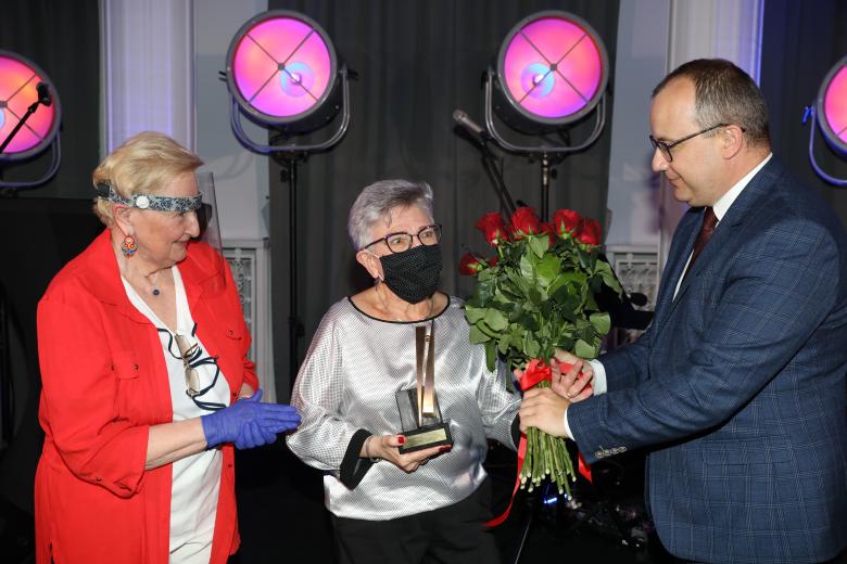 Mężczyzna i kobieta wręczają bukiet kwiatów laureatce nagrody