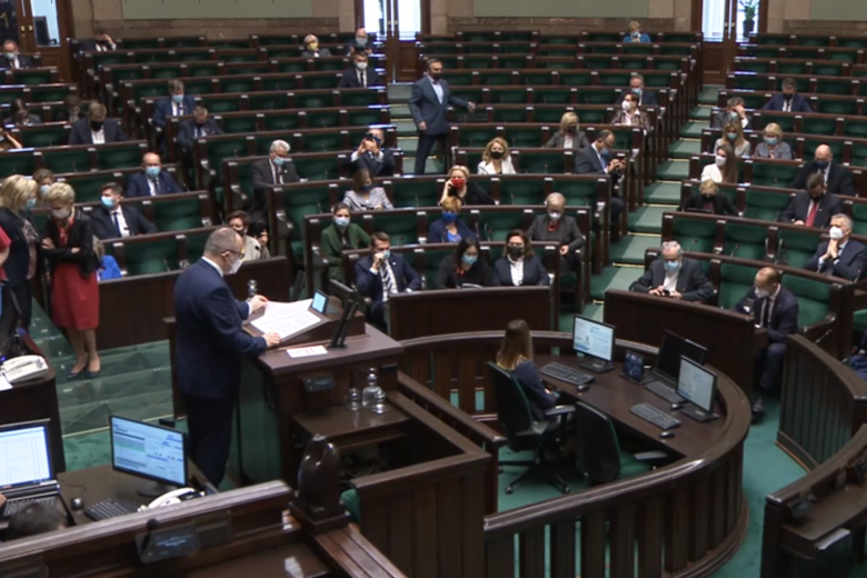 mężczyzna na mównicy w Sejmie, w tle parlamentarzyści
