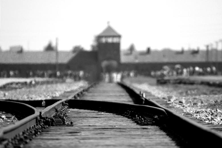 Czarno-białe zdjęcie bramy Auschwitz i rozjazdu kolejowego