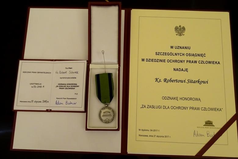 zdjęcie: teczka z dyplomem poświadczającym przyznanie odzanaki honorowej RPO oraz sama odznaka