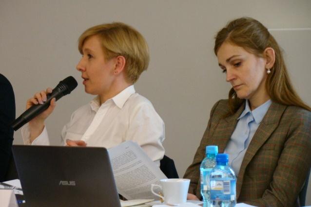 zdjęcie: dwia kobiety siedzą przy stole, kobieta po lewej stroni mówi do mikrofonu, druga z kobiet przeglada dokumenty