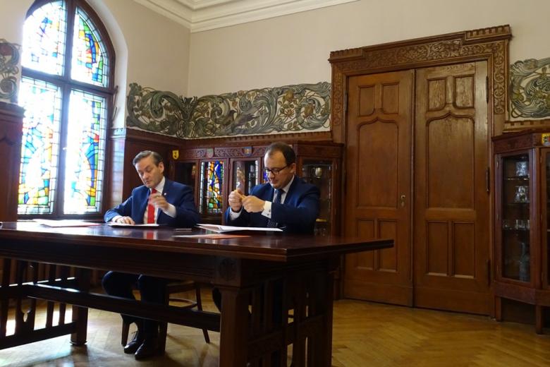 Zdjęcie: dwaj mężczyźni podpisują dokumenty przy stole