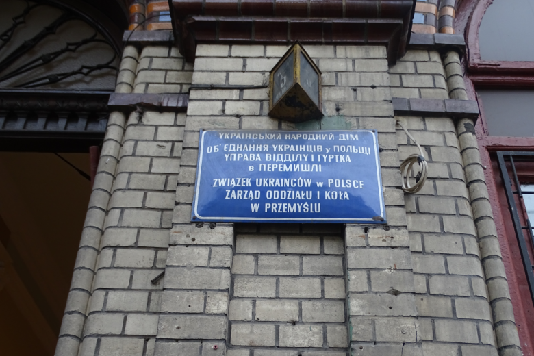 Ściana z niebieską tablicą z napisem po polsku i ukraińsku, że tu się mieści oddział Związku Ukraińców w Polsce