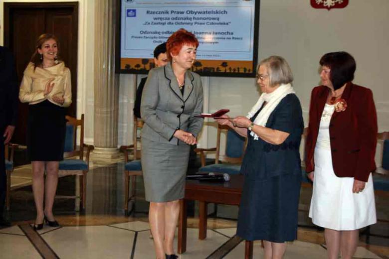 Na zdjęciu Pani Joanna Janocha Prezes Zarządu Głównego PSOUU przekazuje odznakę honorowej RPO Pani Krystynie Mrugalskiej; Honorowemu Prezesowi Stowarzyszenia