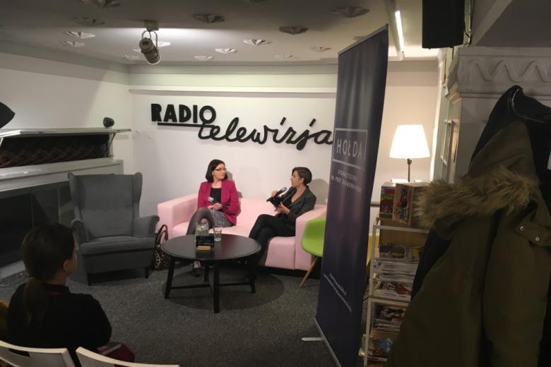 Dwie kobiety rozmawiają na kanapie, na ścianie napis Radio i Telewizja