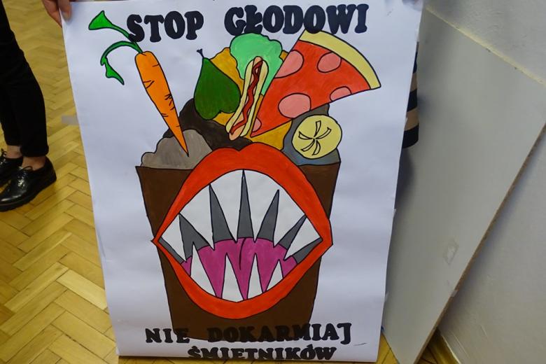 Zdjęcie plakatu, na którym kosz-śmietnik pożera dobre produkty żywnościowe