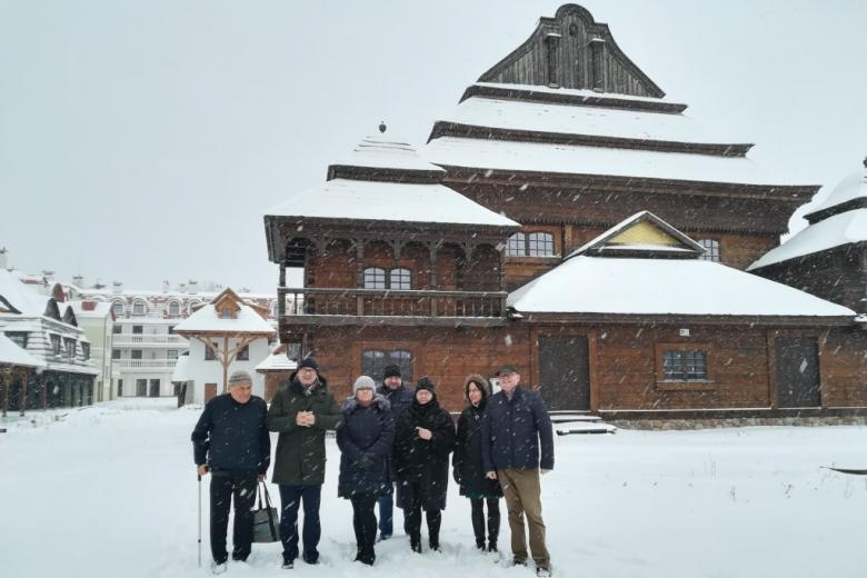 Grupa ludzi w zaśnieżonym drewnianym miasteczku, zdjęcie grupowe