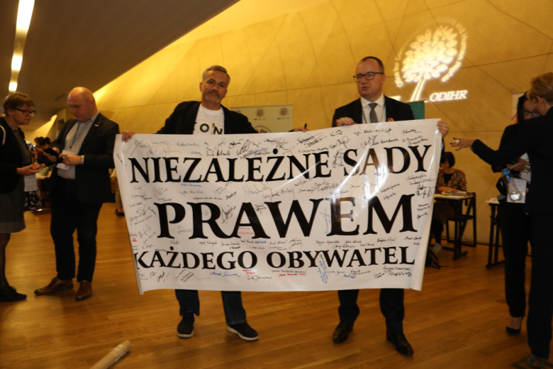 Dwaj mężczyźni trzymają transparent "Niezależne sądy prawem"