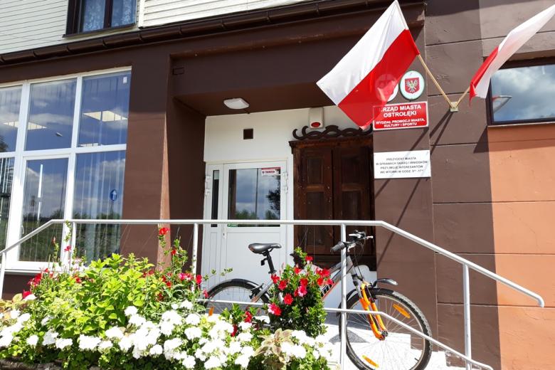 Budynek z biało-czerwoną flagą, przed nim rower