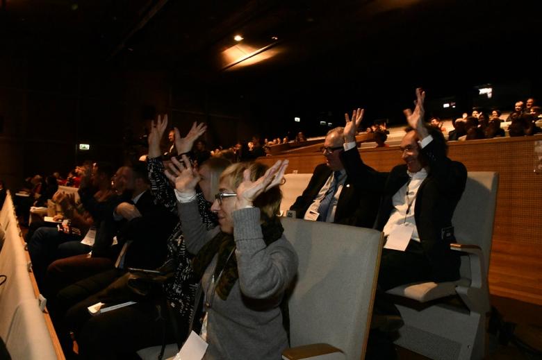 Publiczność w audytorium potrząsa podniesionymi dłońmi