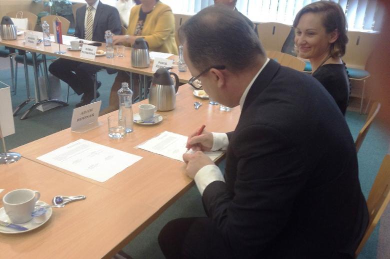 zdjęcie: mężczyzna siedzi przy stole i podpisuje dokument