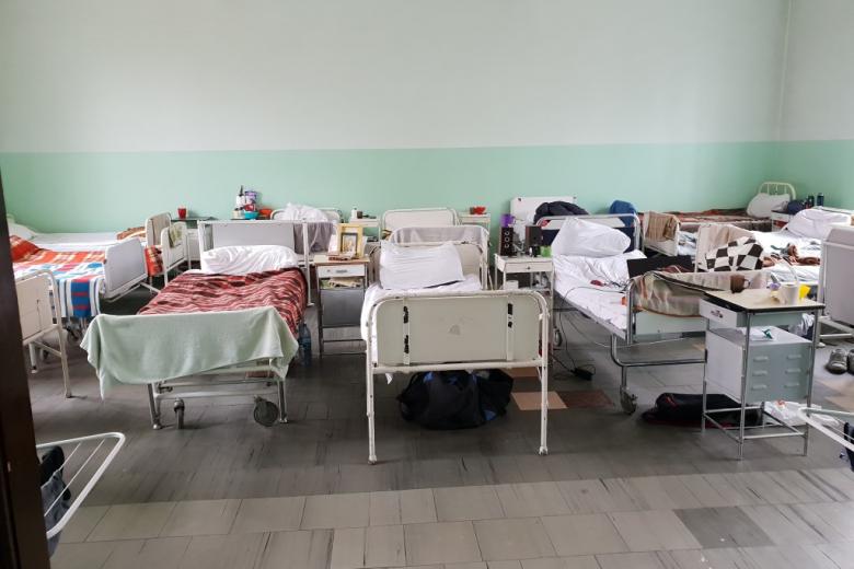 Łóżka szpitalne ustawione w dwuszeregu w dużej sali
