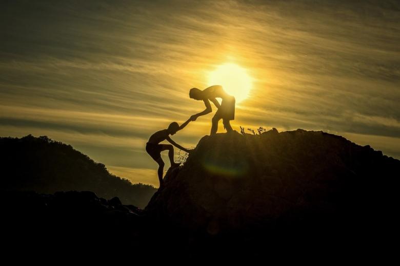 Ludzie pomagają sobie w czasie wspinaczki w górach
