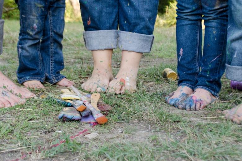Zdjęcie dzieci  - widać tylko gole stopy na ziemi i kolorowe pędzle