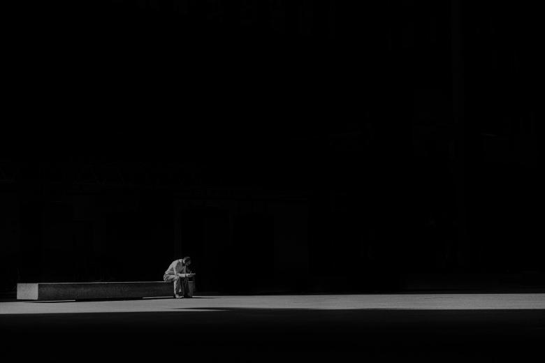 Samotny człowiek w ciemnościach siedzi na ławce