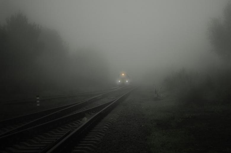 Rozjazd kolejowy. Lokomotywa wyłania się z ciemnej mgły