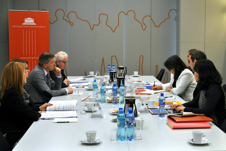 zdjęcie: sześć osób siedzi przy stole  i rozmawia, w tle widać pomarańczowy banner RPO