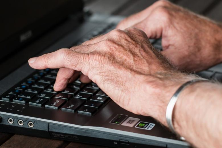 Ręce seniora na klawiaturze komputera