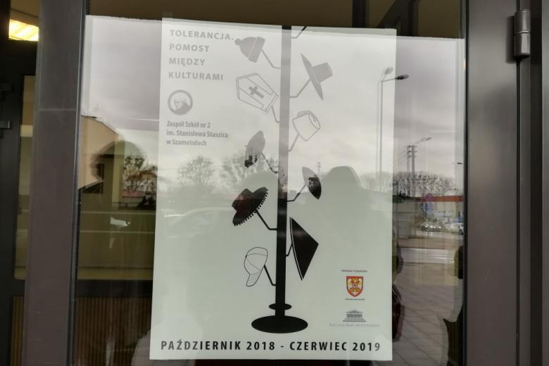 Plakat przedstawiający wieszak z różnymi nakryciami głowy reprezentującymi różne wyznania i style życia