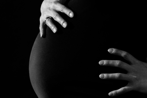 kobieta w ciąży obejmująca brzuch dłońmi