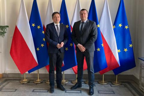 dwóch mężczyzn stoi na tle flag polskich i UE