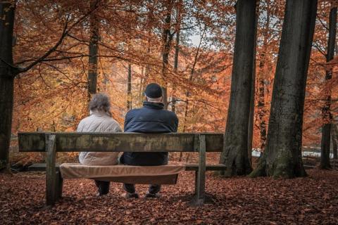 zdjecie dwojga starszych osób siedzących na ławce jesienią w parku 