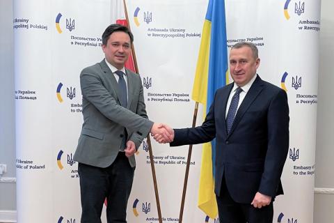 dwóch mężczyzn ściskających dłonie na tle flag Polski i Ukrainy