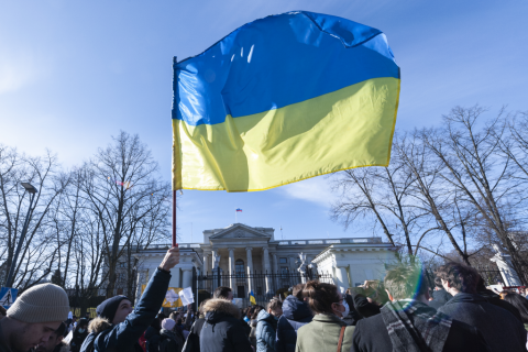 flaga ukraińska trzymana w górze podczas zgromadzenia ludzi  