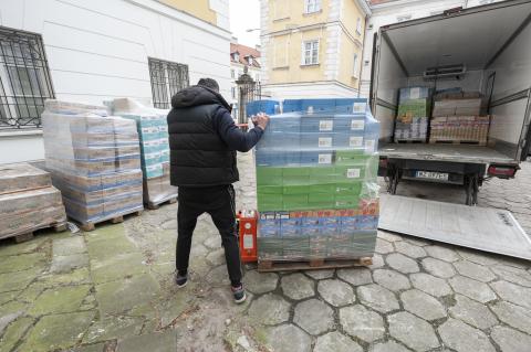 Mężczyzna wyładowujący z samochodu ciężarowego palety produktów spożywczych na dziedzińcu biura RPO