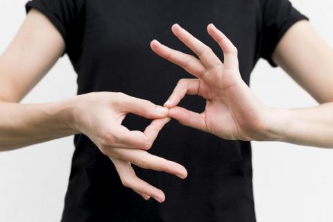 osoba układająca dłonie w znak języka migowego