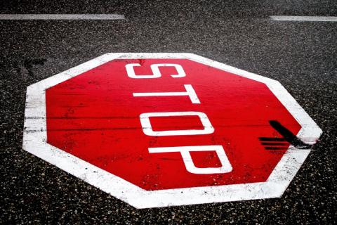 Poziomy znak z napisem stop na czerwonym tle wymalowany na ulicy