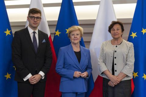 ZRPO Hanna Machińska, ZTPO Valeri Vachev i Komisarz Gillian Triggs pozują na tle flag polskich i UE