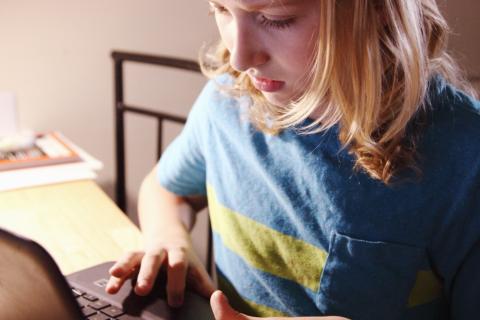 młoda dziewczyna z bluzką w kolorach Ukrainy przy komputerze