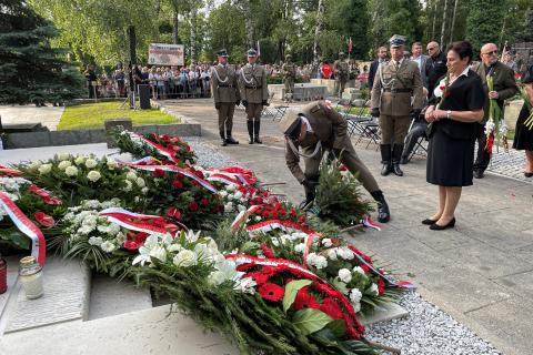 Żołnierz składa wieniec Biura RPO pod pomnikiem. Za nim stoi ZRPO Hanna Machińska, trzymająca w dłoniach pojedynczy kwiat.