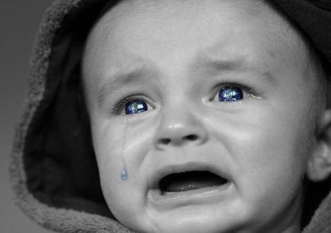 Zbliżenie na twarz kilkumiesięcznego dziecka , które płacze, a po policzkach płyną mu łzy
