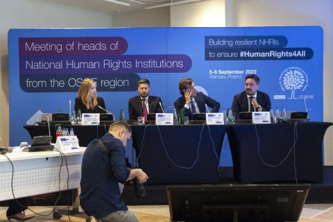 Cztery osoby, w tym RPO Marcin Wiącek, siedzą za stołem prezydialnym na konferencji. W tle plansza z napisem "Meeting of heads of National Human Rights Institutions from OSCE region