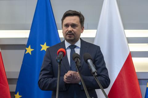 RPO Marcin Wiącek wypowiada się do mikrofonów na tle flag Polski i Unii Europejskiej