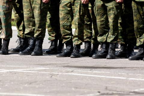 Nogi kilkunastu żołnierzy stojących w umundurowaniu na placu