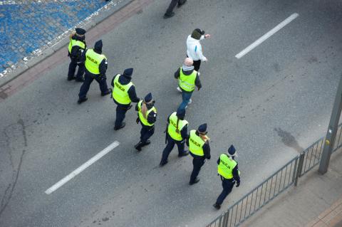 policjanci idący całą szerokością jezdni