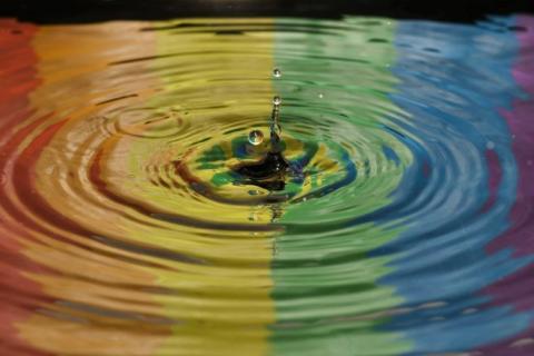 Kropla wpada do wody z odbijającymi się w niej kolorami 