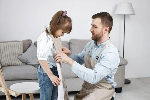 Ojciec pomaga się ubrać córce z niepełnosprawnością