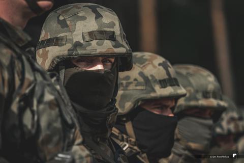 Żołnierze w umundurowaniu polowym i zamaskowanymi twarzami stoją w szeregu
