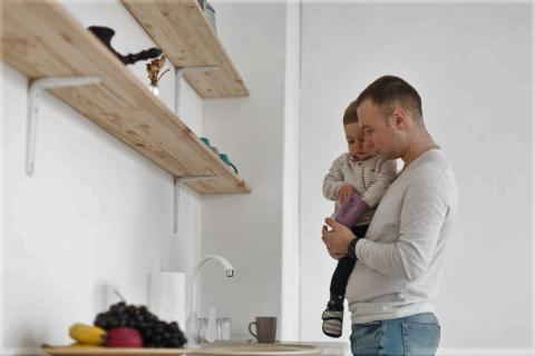 ojciec trzyma dziecko na rękach w kuchni 