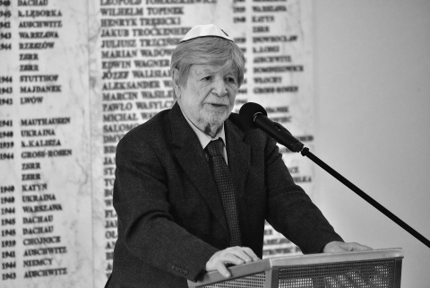 Czarno-białe zdjęcie przedstawiające mężczyznę przemawiającego przy mównicy z mikrofonem